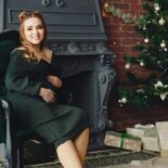 Die 10 schönsten Weihnachtsoutfits für Damen: von glamourös bis gemütlich Elegante junge Dame, die neben einem Weihnachtsbaum sitzt