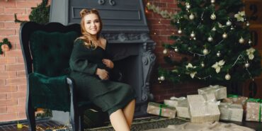 Elegante junge Dame, die neben einem Weihnachtsbaum sitzt